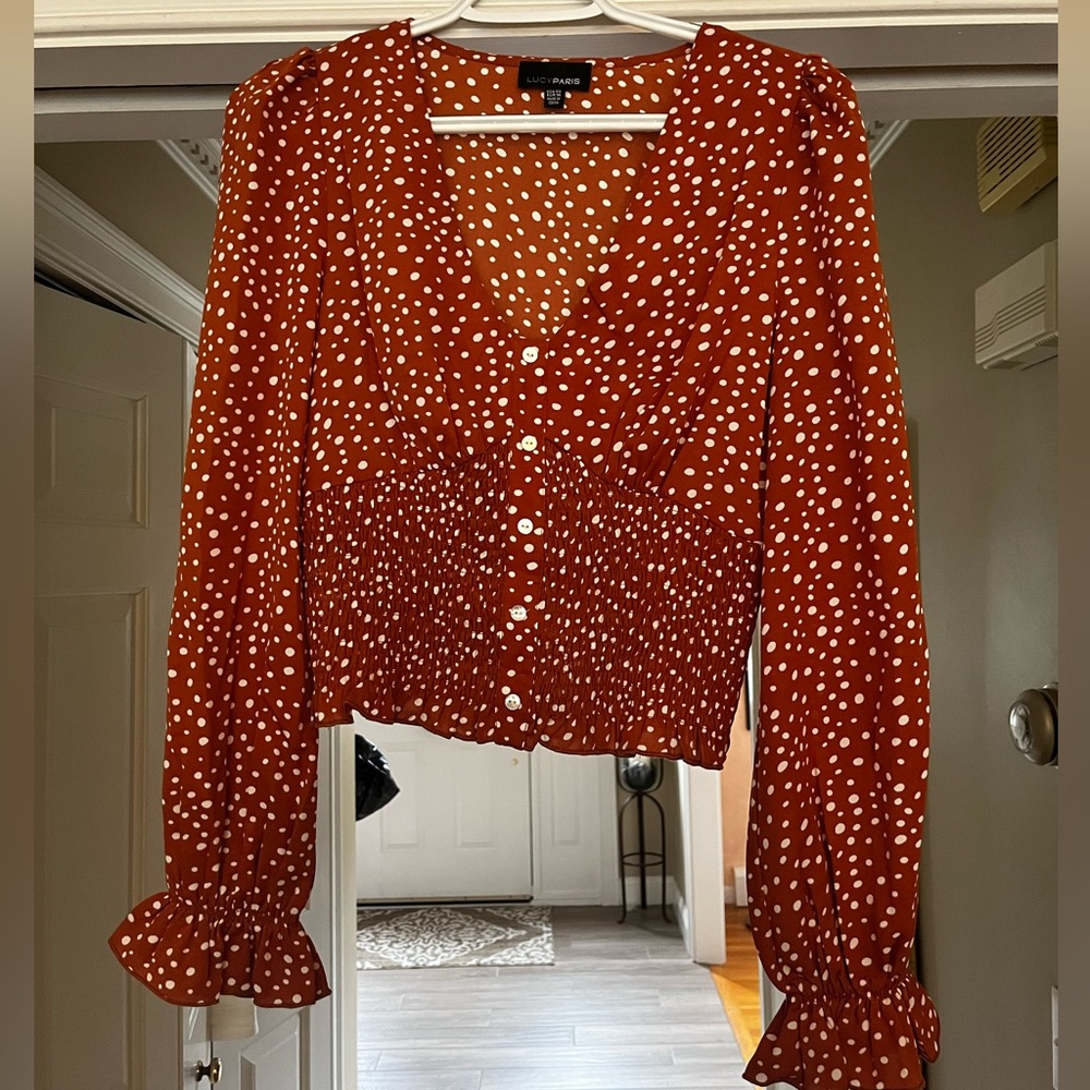 Burnt orange shirt with polka dots. Corset. Frilled sleeve.